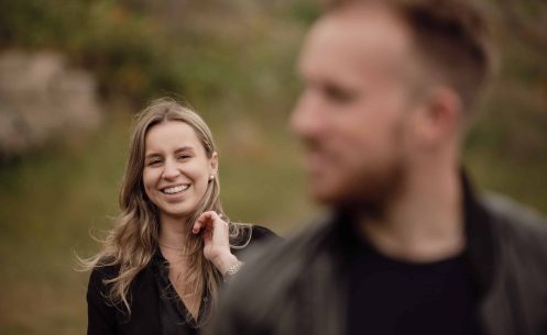 A man and woman are smiling at each other in a field.